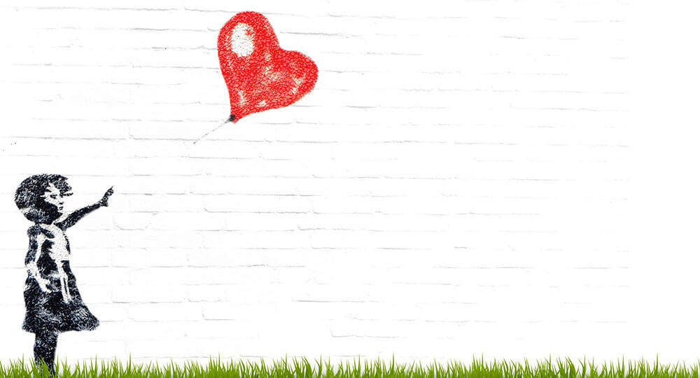 Zeichnung an einer Wand von einem Mädchen lässt einen roten Herz Ballon los